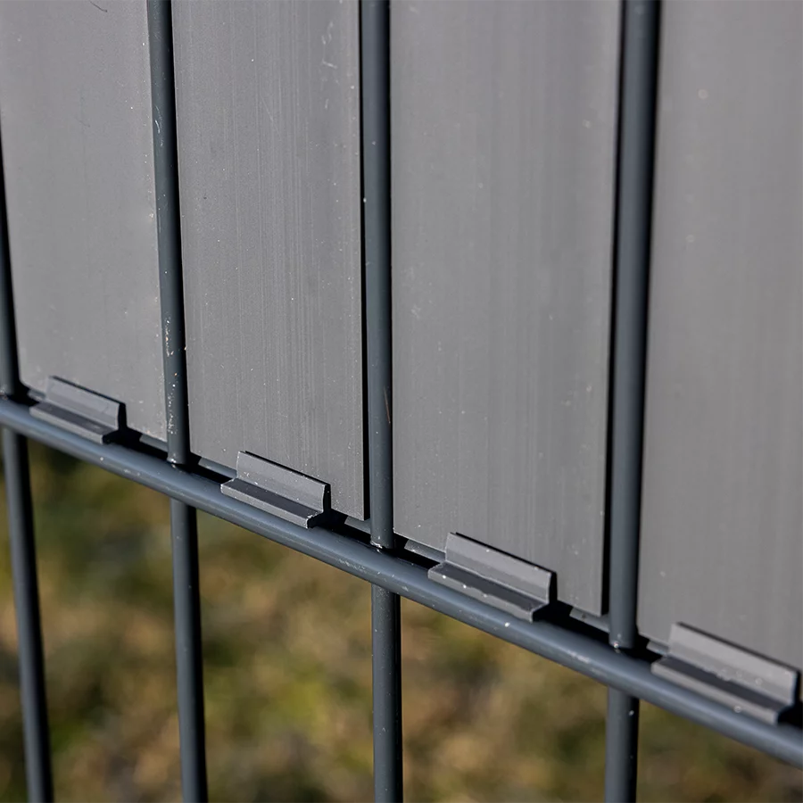 Detailansicht eines modernen Doppelstabmattenzauns mit schieferfarbenen Sichtschutzpaneelen und Befestigungsclips von Wodewa